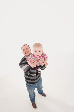 Happy smiling father lifting up a baby boy. Top view isolated portrait on the white background. Family concept.の写真素材