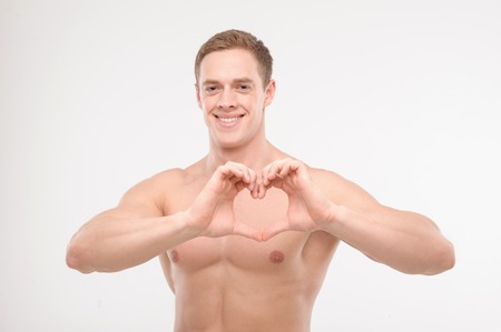 Healthy young muscular man, athlete showing heart with hands, waist up portrait isolated on white  Concept of sportの写真素材