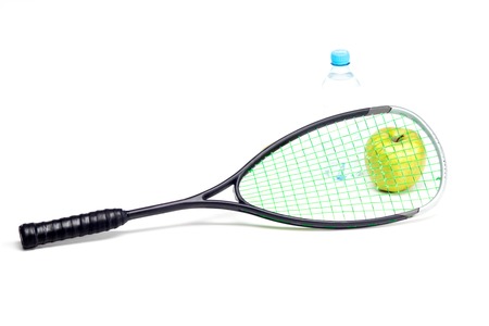 Green apple and water bottle behind sport racket isolated on whiteの写真素材