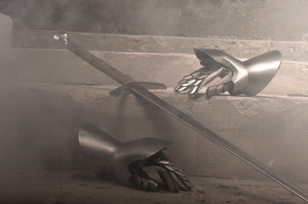 Closeup portrait of medieval armor metal gloves and sword on stone steps の写真素材