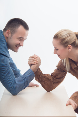Waistup portrait of a young attractive woman and man fighting on hands isolated on white backgroundの写真素材