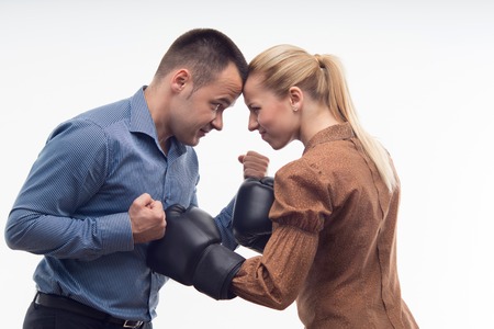 Young attractive business woman in boxing gloves attacking man with fists, isolated on white backgroundの写真素材