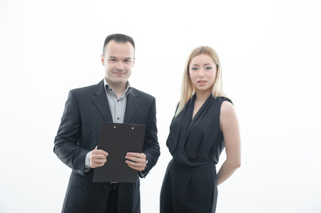 Angry boss businessman with blank paper and embarrassed young attractive woman employee holding head and looking at camera, isolated on whiteの写真素材