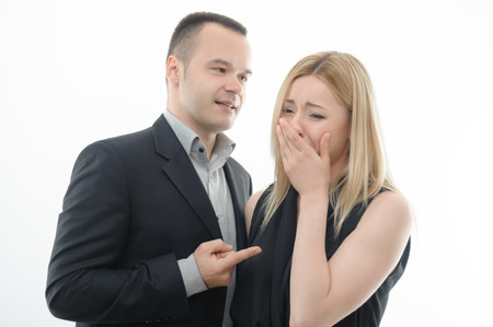 Colleagues arguing, boss shouting and pointing at crying young attractive woman, isolated on whiteの写真素材