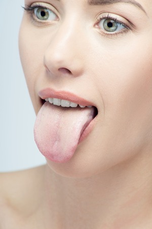 Closeup portrait of attractive seductive woman with her tongue out isolated on white backgroundの写真素材