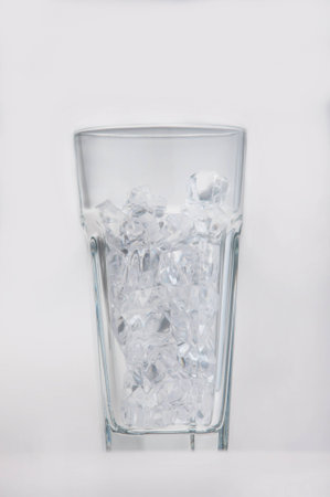 Empty glass filled with ice cubes isolated on whiteの写真素材