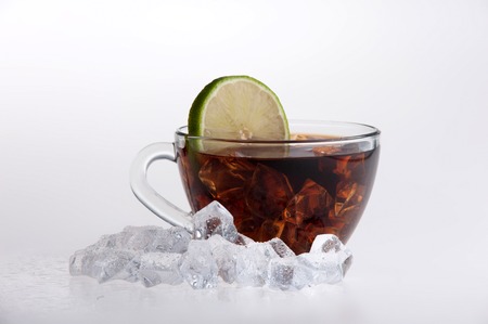 Iced tea with lemon and mint surrounded by ice cubes isolated on white background