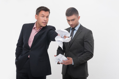 Senior and junior business people in elegant suits  Boss angry with employee looking down, holding crumpled paper isolated on whiteの写真素材