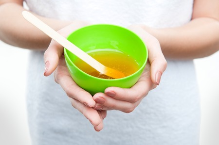 Closeup portrait of young woman in towel preparing natural homemade organic facial mask of honey, isolated on whiteの写真素材