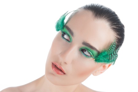Closeup portrait of beautiful brunette young woman with peacock style make-up looking aside isolated on white backgroundの写真素材