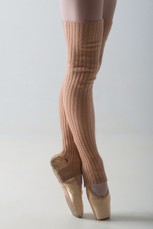 Closeup portrait of a dancer, legs in ballet shoes and long socks dancing in pointe isolated on white backgroundの写真素材
