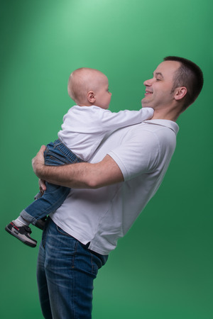 Half-length portrait of happy smiling handsome father and his son baby boy playing around and laughing, family concept, isolated on green backgroundの写真素材