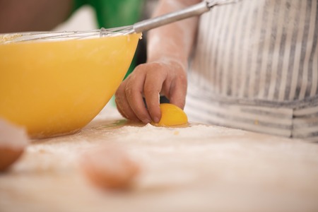 Closeup portrait of little child cooking egg yolk  Bowl, mixer and flour on kitchen tableの写真素材