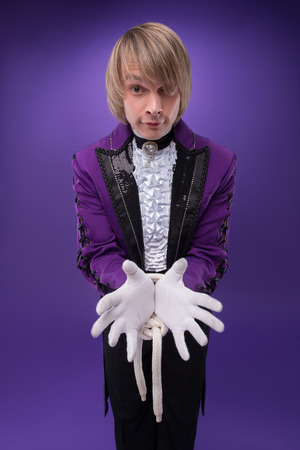  Half-length portrait of juggler wearing splendid violet jacket white shirt and black pants standing with tied hands  Isolated on blue backgroundの写真素材