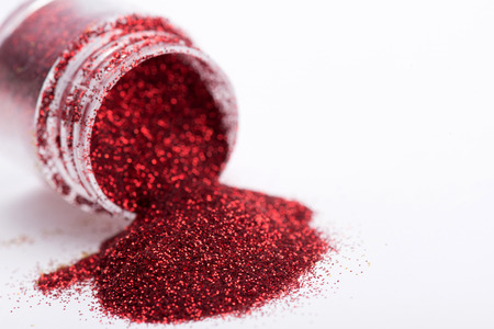 Close-up view of  powder eyeshadows  in red pouring from the eyeshadow pot , isolated on white backgroundの写真素材
