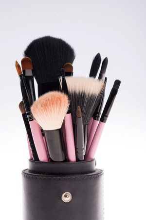 Close-up of Set of 14 professional  different sizes make-up brushes with natural  black and brown bristle,  black ferrule, pink handle  in black tube isolated on white backgroundの写真素材