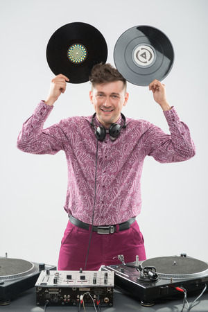 Half-length portrait of excited young DJ with stylish haircut, bow tie having fun with vinyl record showing Mickey Mouse ears isolated on white backgroundの写真素材
