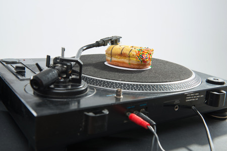 Close-up portrait of donut placed on vinyl record and turntable, isolated on white backgorundの写真素材