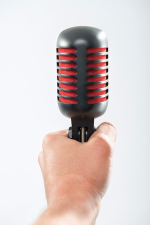 Closeup portrait of male hand holding a retro microphone isolated on whiteの写真素材