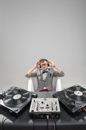 Top view of confident young DJ with stylish haircut and glasses and headphones in the bath near on mixer isolated on white backgroundの写真素材