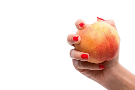 Woman with nice red polished nails holding ripe delicious peach. Isolated on white backgroundの写真素材