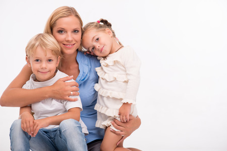 Happy family of mother  son and daughter smiling  embracing  looking  at camera  isolated on white background with copy placeの写真素材