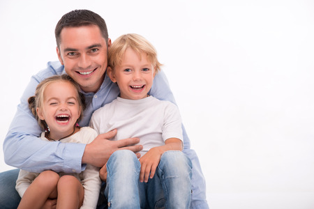 Happy family of father  son and daughter smiling  embracing  looking  at camera  isolated on white background with copy placeの写真素材