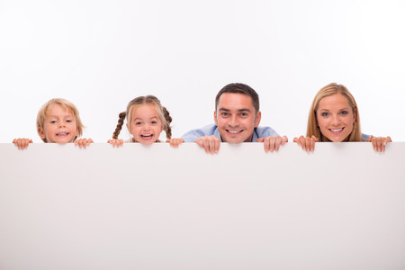 Happy family of father mother son and daughter smiling  looking  out wall  isolated on white background with copy placeの写真素材