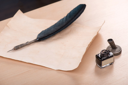 ink and beautiful artificial black feather  on old yellow paperの写真素材