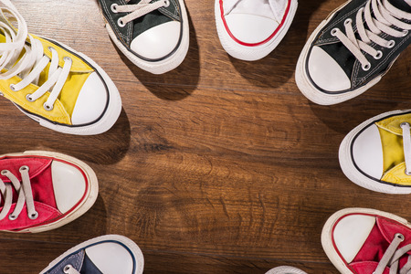 cool youth white yellow red blue black  gym shoes standing in circle  on brown parquet  wooden floor...