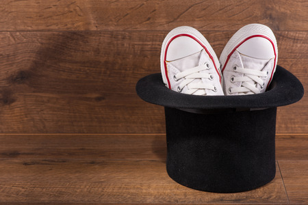 cool youth white gym shoes with red  stripes  on brown parquet  in black top hat like  rabbit wooden...