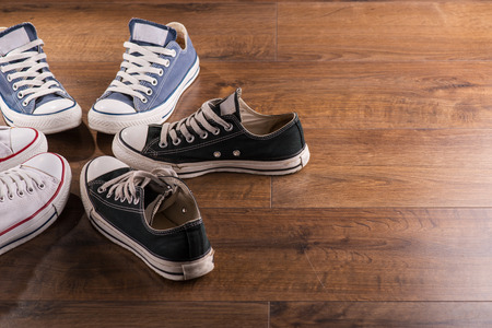 cool youth white blue black  gym shoes standing in circle  on brown parquet  wooden floor top view  with copy placeの写真素材