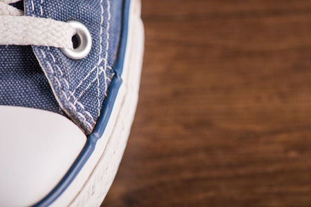 cool blue  gym shoes with white laces  on brown parquet  wooden floor  close up  with copy placeの写真素材