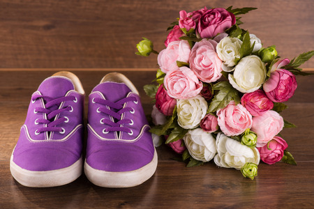 cool youth violet   shoes near bunch of roses on brown parquet  wooden floorの写真素材