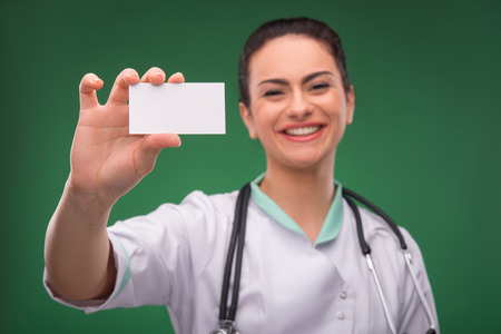 Portrait of beautiful happy  woman doctor with stethoscope with  sheet of paper  looking at camera waist up with copy placeの写真素材