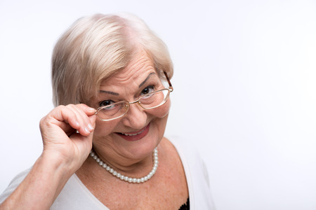 Curious granny looking through her glassesの写真素材