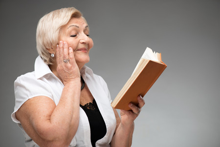 Elderly woman holding yellow bookの写真素材