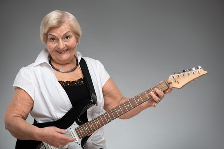 Elderly woman holding the guitarの写真素材
