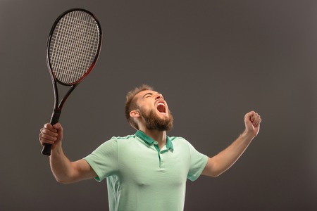Handsome young man in polo shirt holding tennis racket