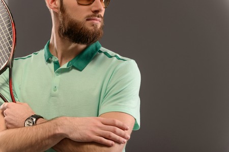 Handsome young man in polo shirt holding tennis racket