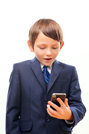 Business child in suit and tie posing with cell phoneの写真素材