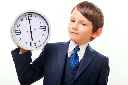 Business child in suit and tie posing with clockの写真素材