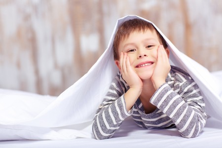 Portrait of a cute little boy under the blanketの写真素材