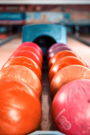 Close up of bright red bowling ball lying in the rows of other colorful ballsの写真素材