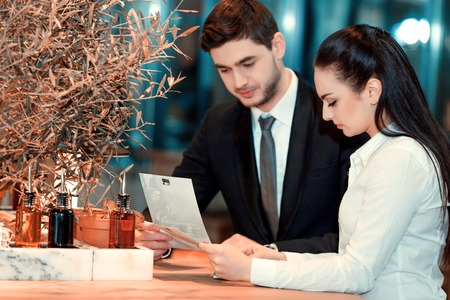 Managers at work. Image of beautiful young woman and man in formalwear looking at leaflets while sitting at the restaurantの写真素材