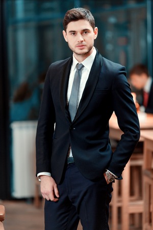 Confidence and charisma. Cheerful young businessman in full suit looking at camera while standing in the bar during business lunchの写真素材