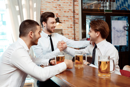Friends meeting. Close up on colleagues shaking hands during meeting in the barの写真素材