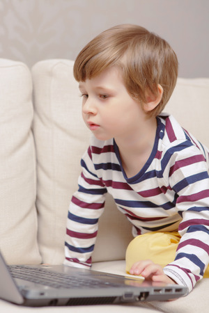 Young learner. Close-up of a small boy using laptop at homeの写真素材