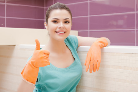 Top mark. Pretty smiling woman showing sign OK in orange rubber glovesの写真素材