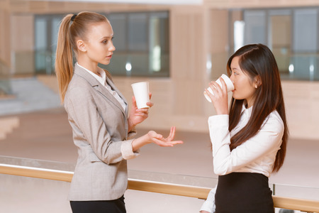 Coffee break. Young businesswomen discussing business matters and drinking coffee during the coffee break at the meetingの写真素材